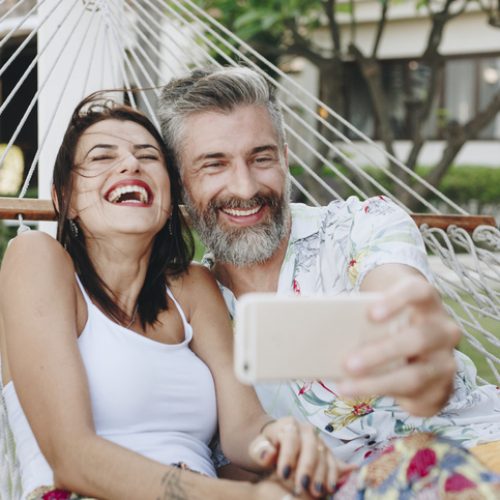 A woman and a man taking a selfie in a hammock
