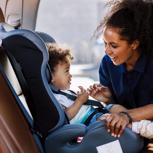 Mother securing baby in car seat